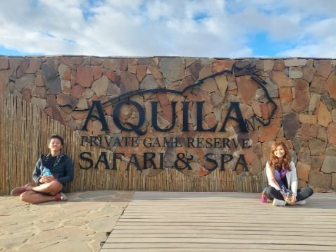 Me and my wife sitting next to the Aquila Safari Reserve logo