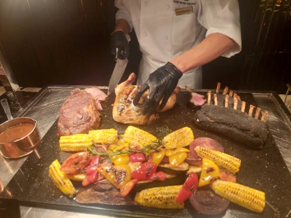 A chef cutting big steak with black truffle lamb nearby